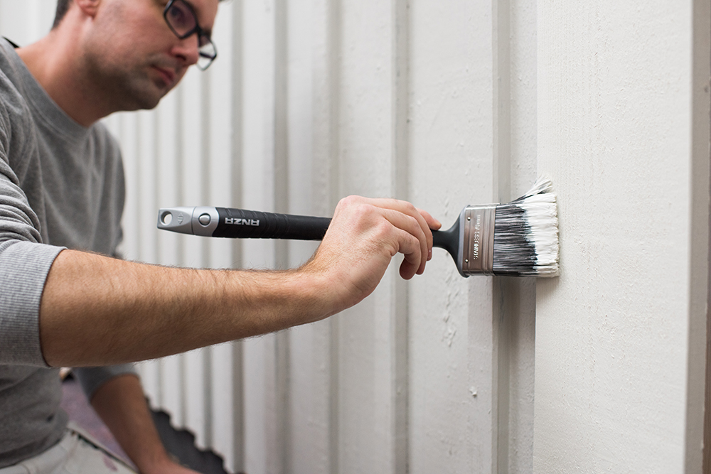 Man använder platinum lång vinkelpensel för att måla fasad och husvägg